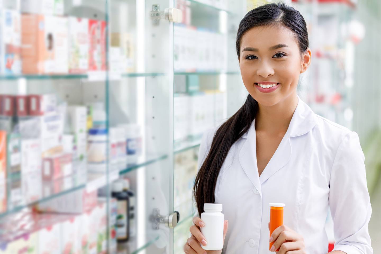 Smiling pharmacist holding two medication bottles