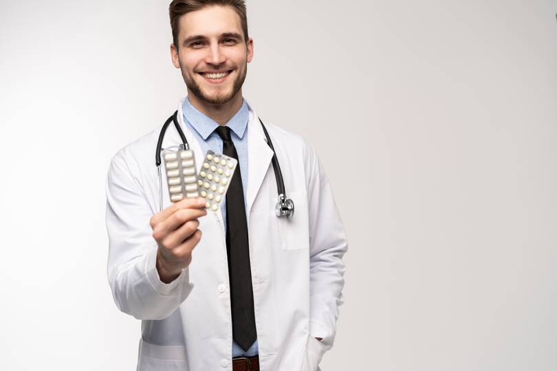 Male pharmacist displaying two medication blister packs